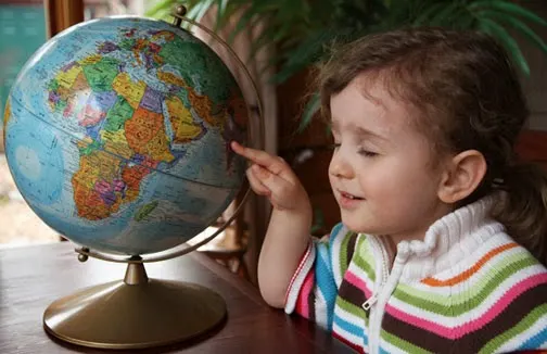 child closing eyes pointing to globe