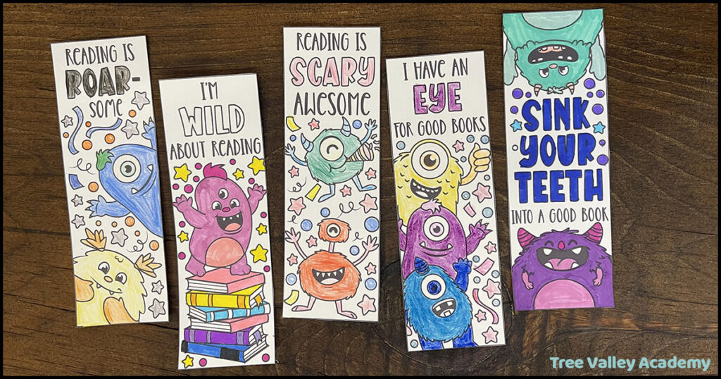 Five colorful monster bookmarks with fun reading sayings displayed on a wooden surface.